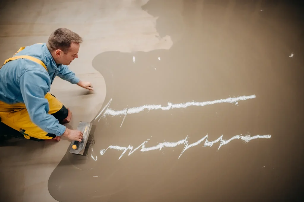 Concrete flooring installer applying a concrete microtopping to a floor's substrate.